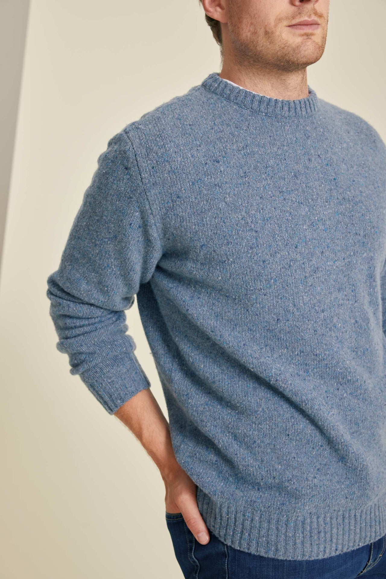 Man wearing a blue knitted sweater against a plain background