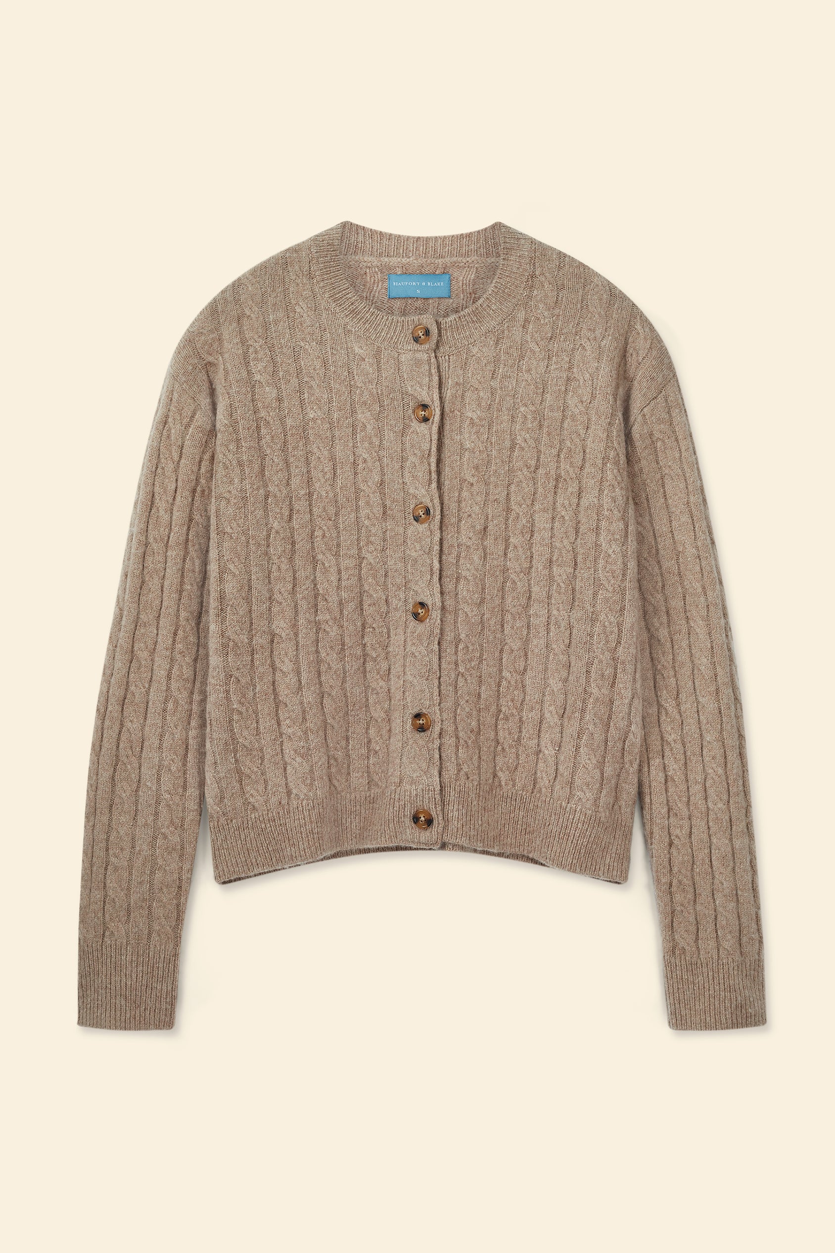 Brown cable knit cardigan on a beige background