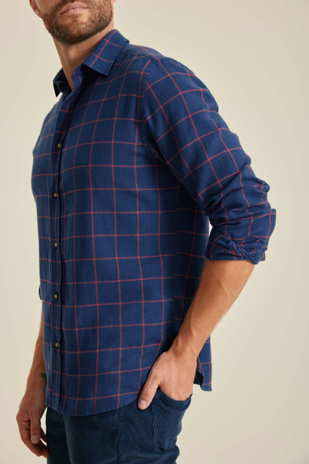 Man wearing a blue plaid shirt against a beige background