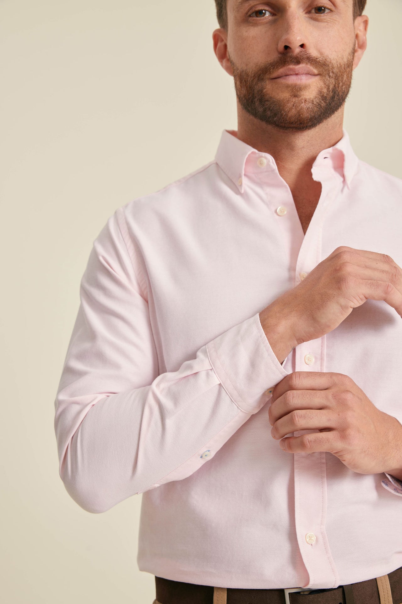 Man wearing a light pink dress shirt against a plain background