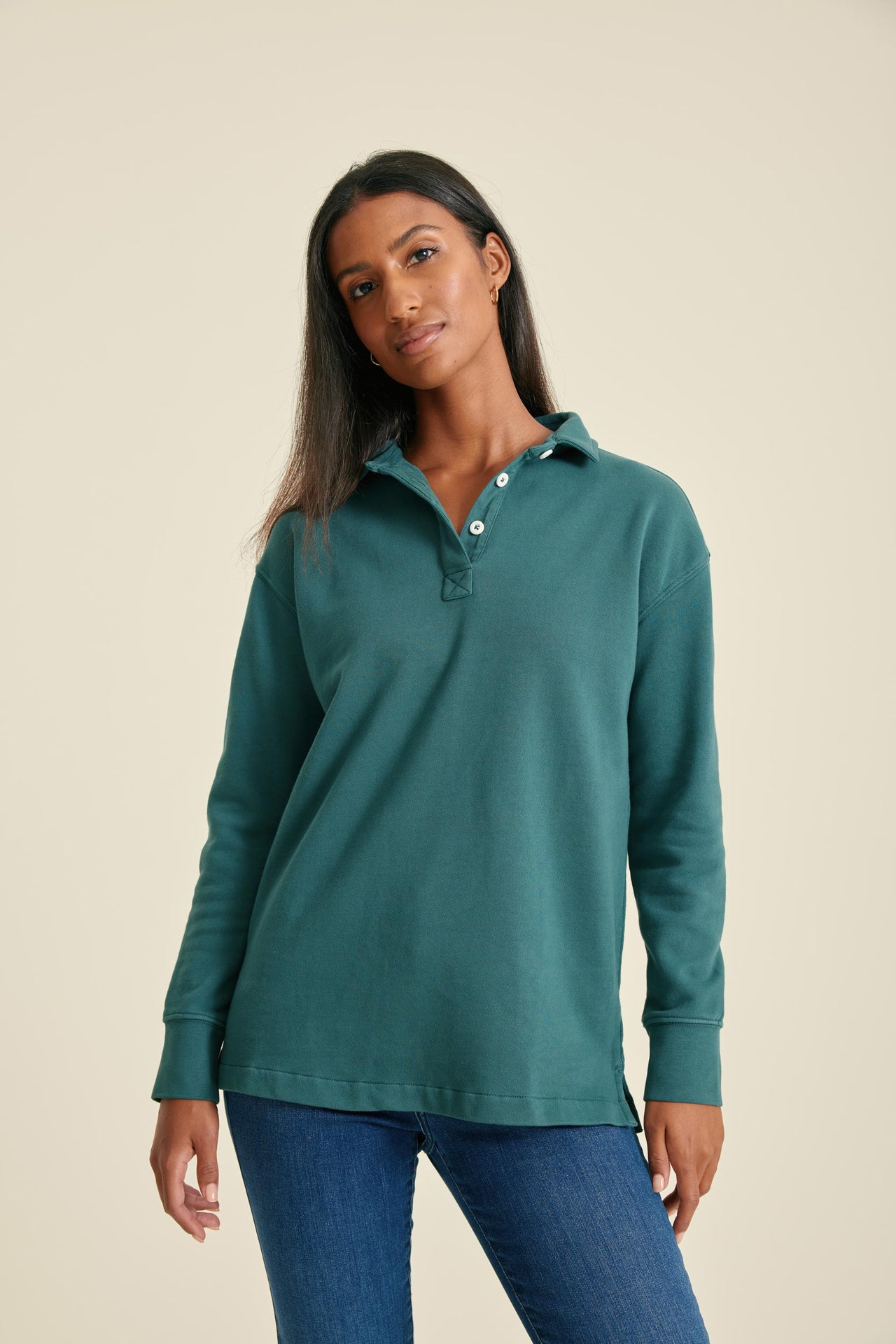 Woman wearing a pine sweat with buttons on a beige background