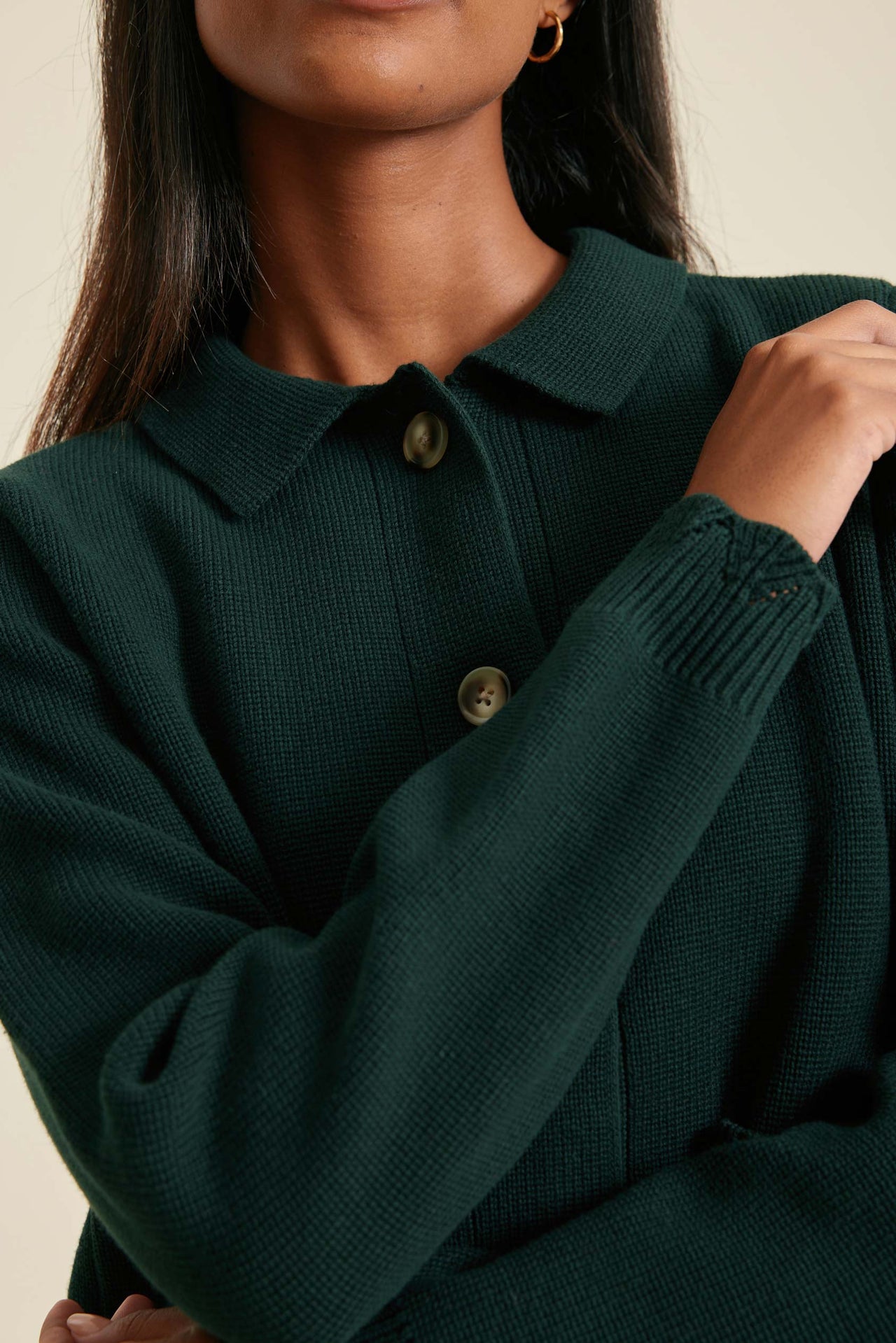 Person wearing a dark green sweater with a neutral background