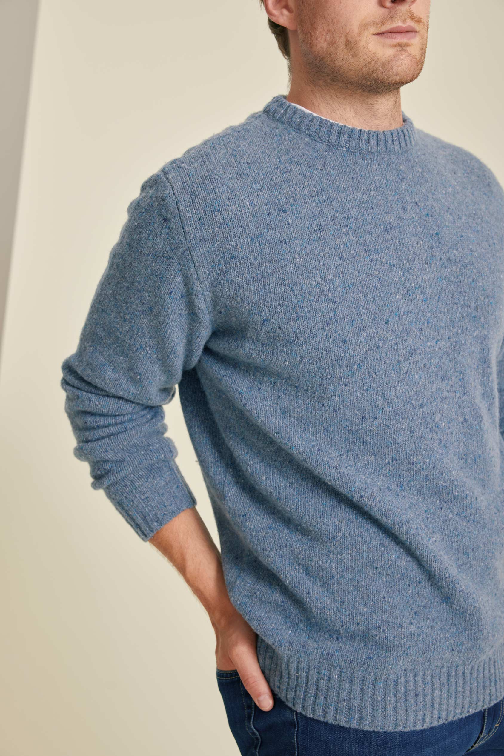 Man wearing a blue knitted sweater against a plain background