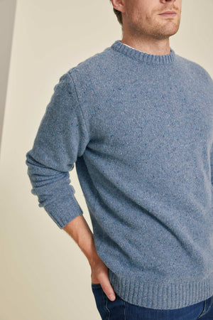 Man wearing a blue knitted sweater against a plain background