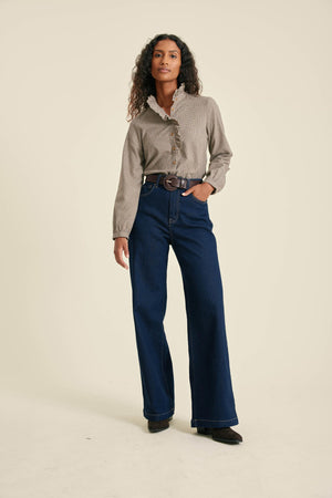 Woman wearing a beige shirt and blue jeans on a beige background