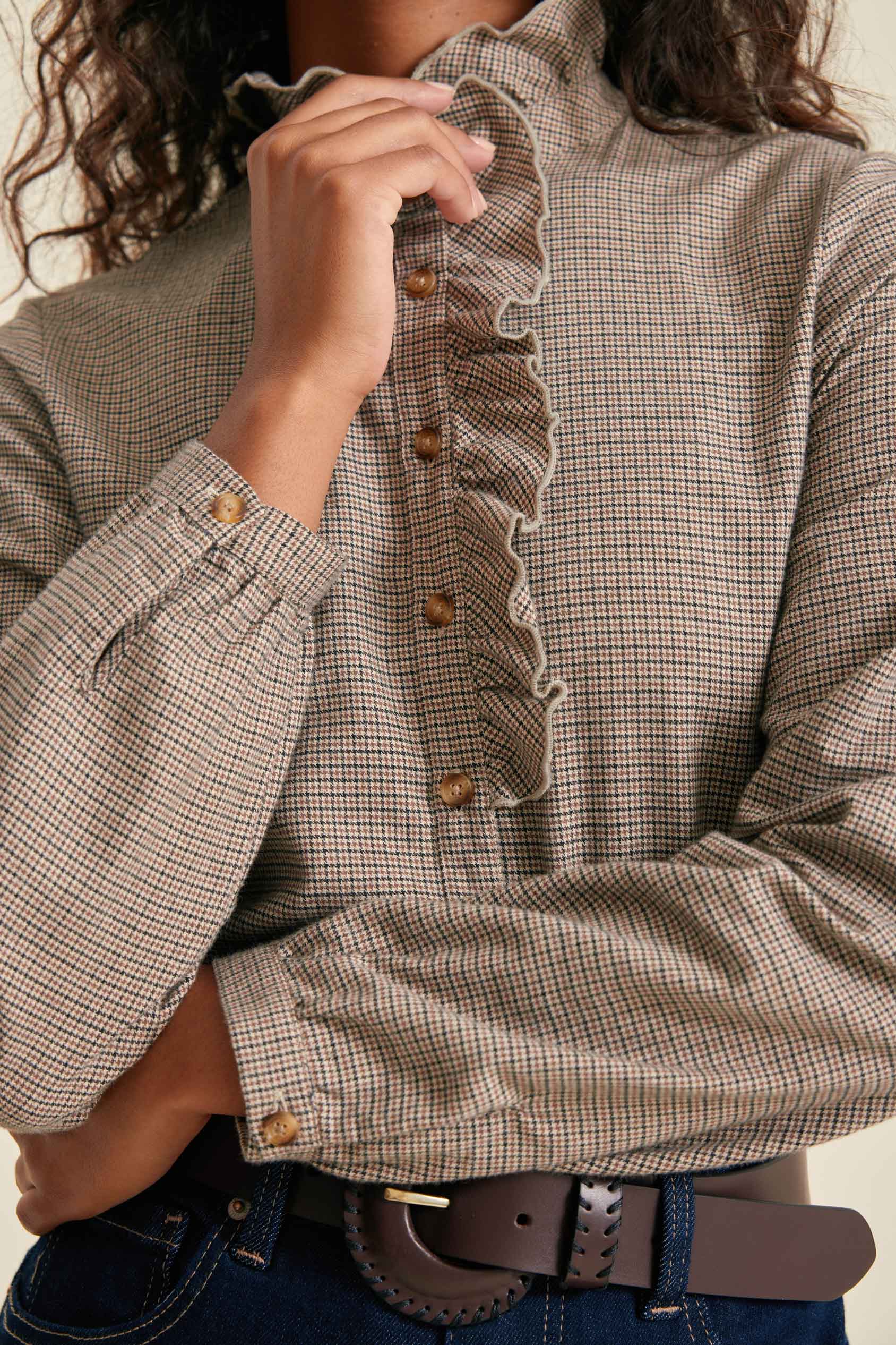 Close-up of a person wearing a checkered blouse with ruffled details.