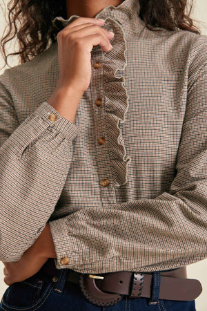 Close-up of a person wearing a checkered blouse with ruffled details.