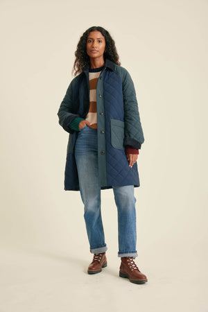 Woman wearing a blue quilted coat on a beige background