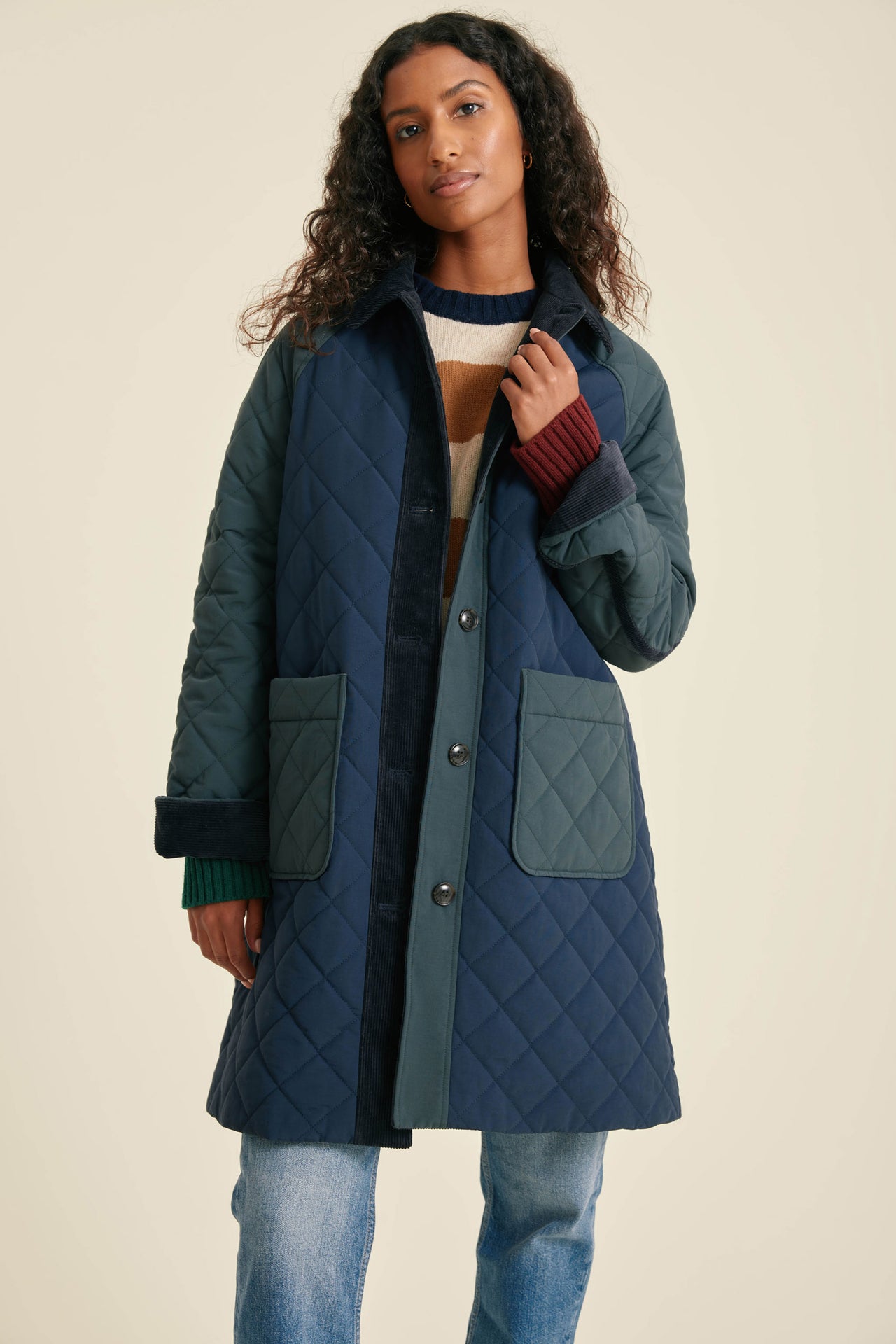 Woman wearing a blue quilted coat on a beige background