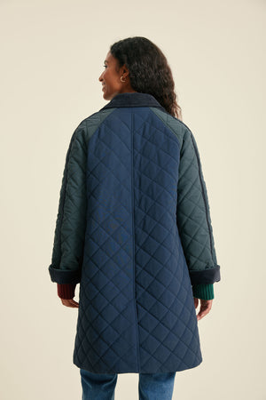 Person wearing a long quilted coat on a beige background