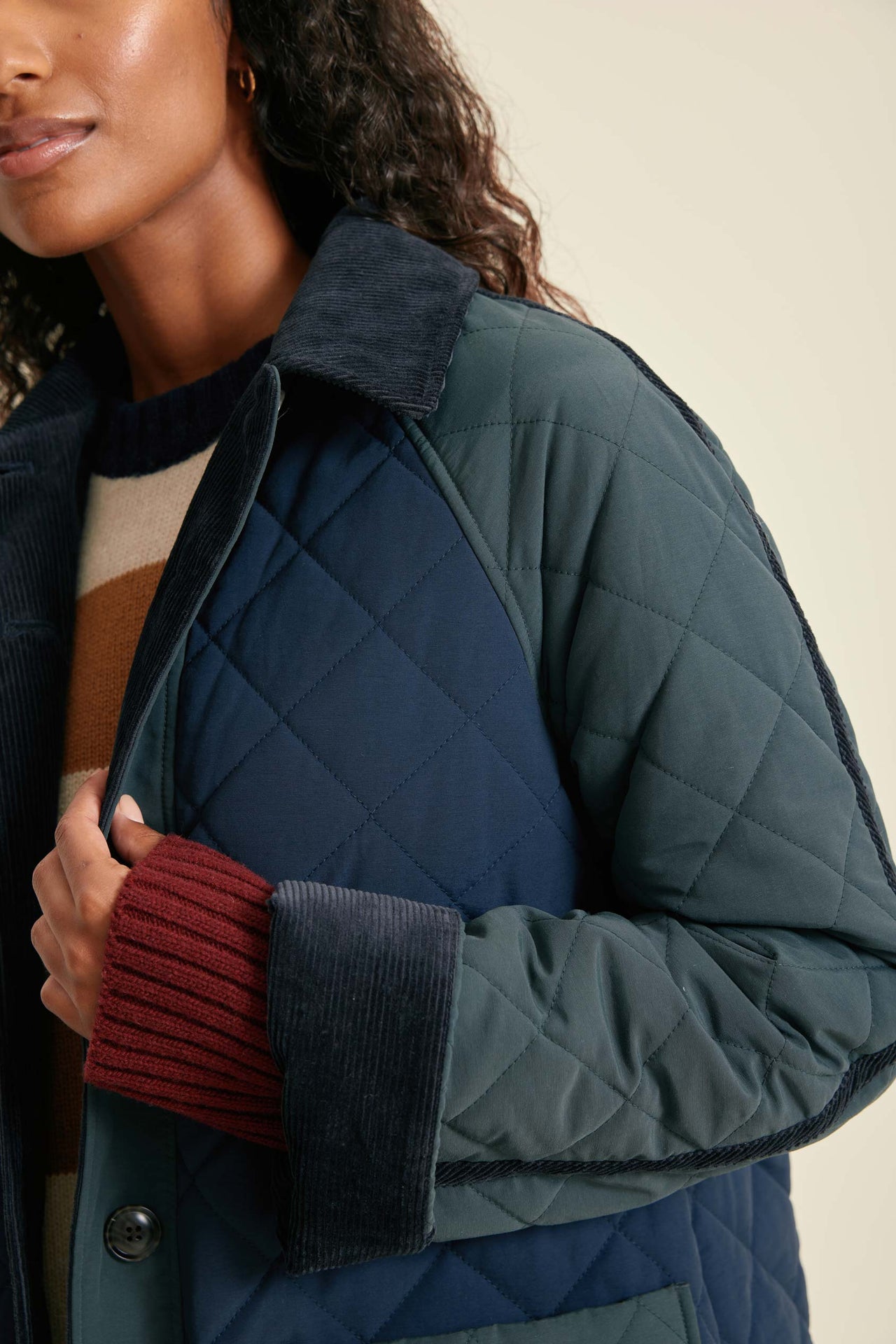 Person wearing a quilted jacket with a neutral background