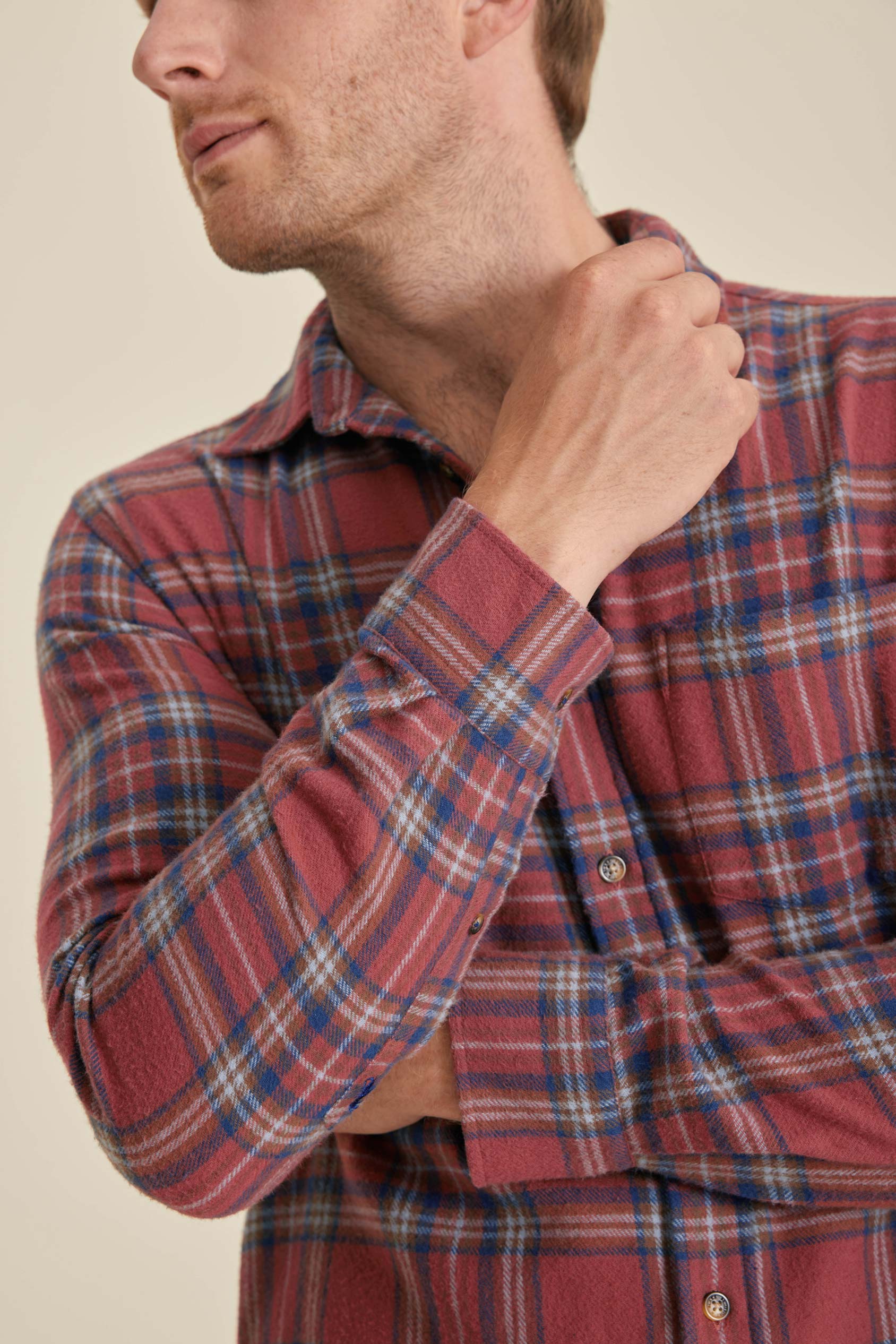 Man wearing a red plaid shirt against a beige background