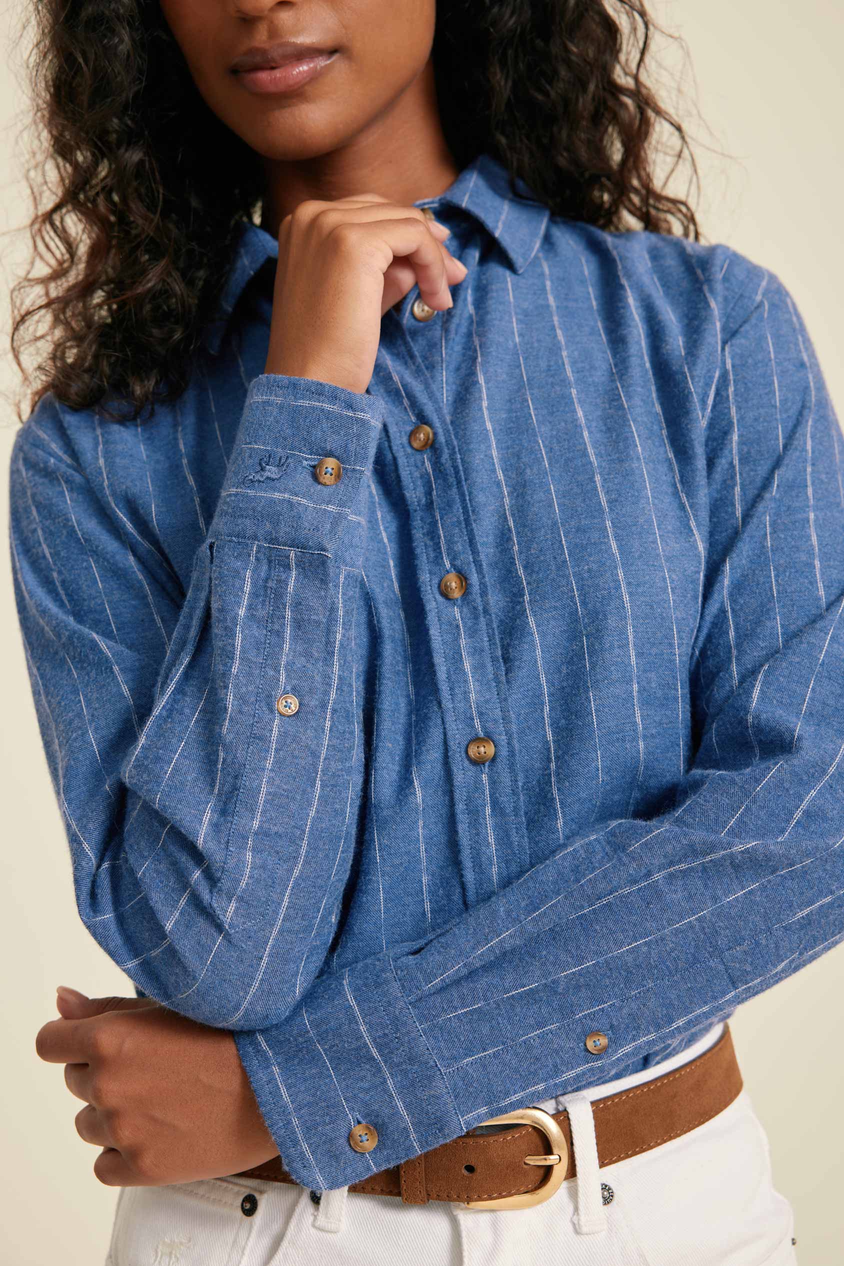 Woman wearing a blue pinstripe shirt with a beige background