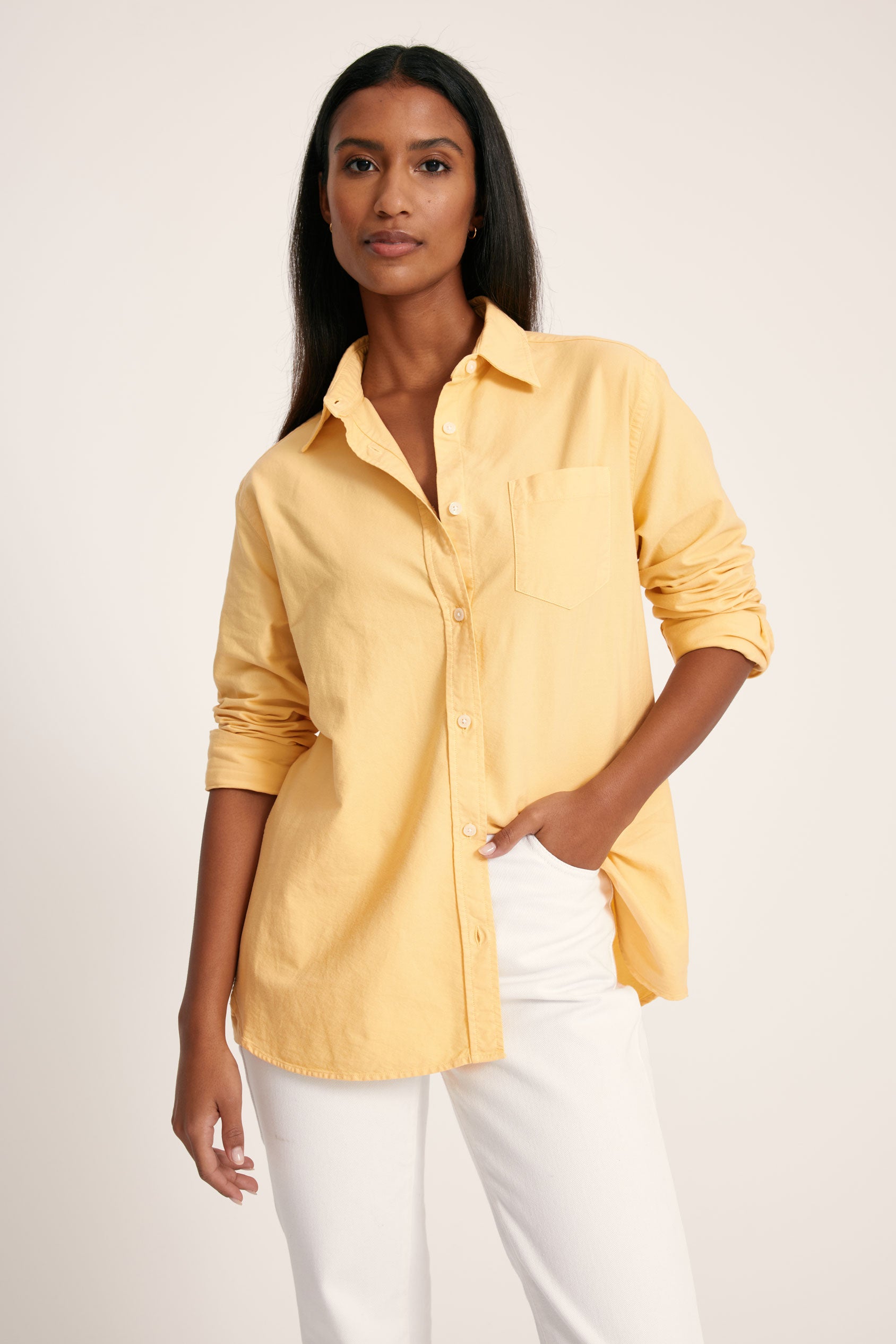 Woman wearing a yellow shirt and white pants on a plain background