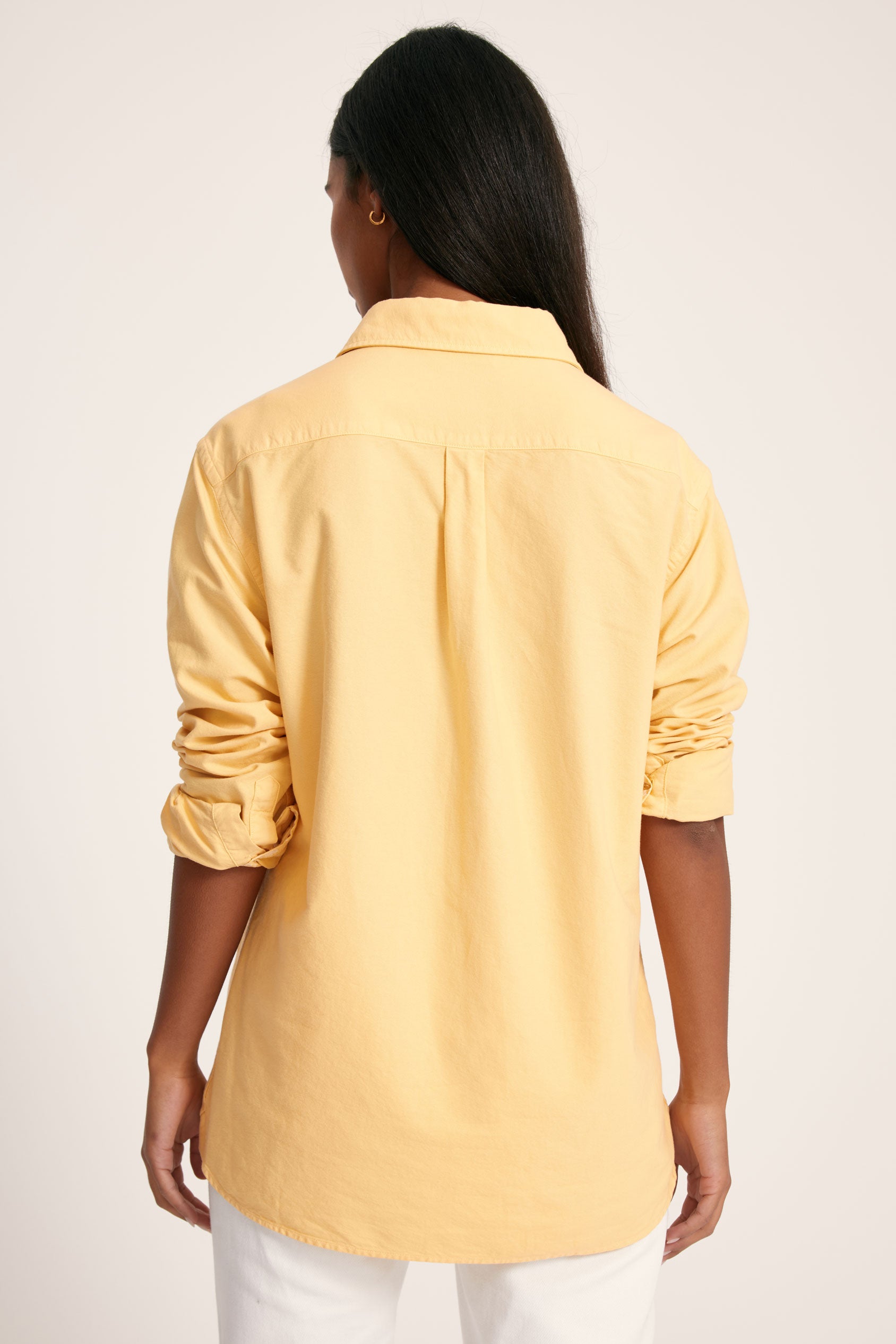 Person wearing a yellow shirt on a plain background