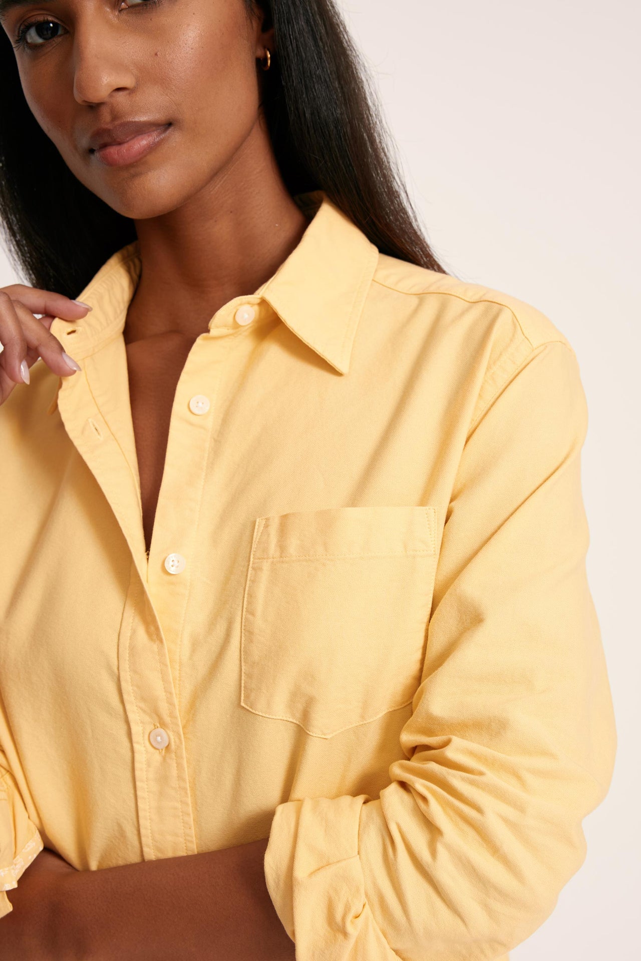 Woman wearing a yellow shirt against a plain background