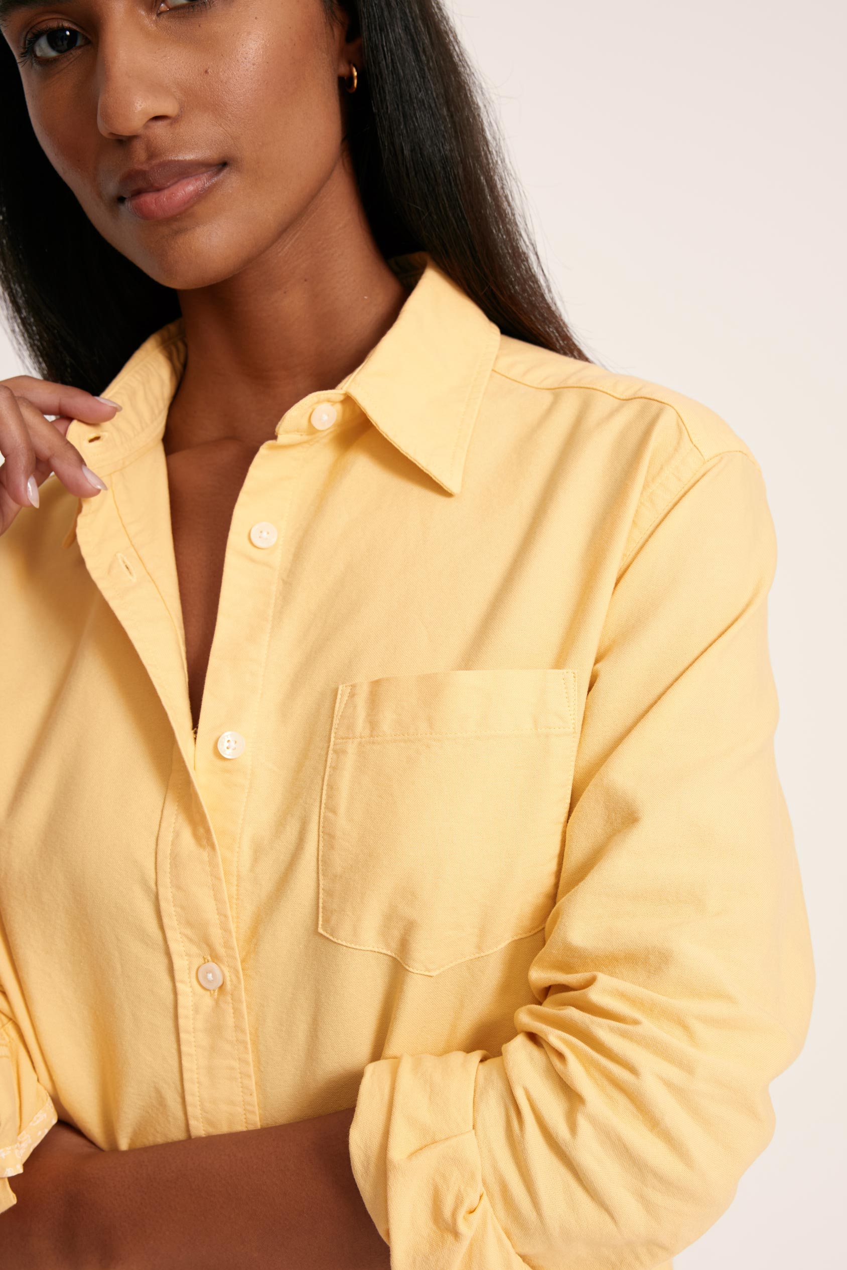 Woman wearing a yellow shirt against a plain background