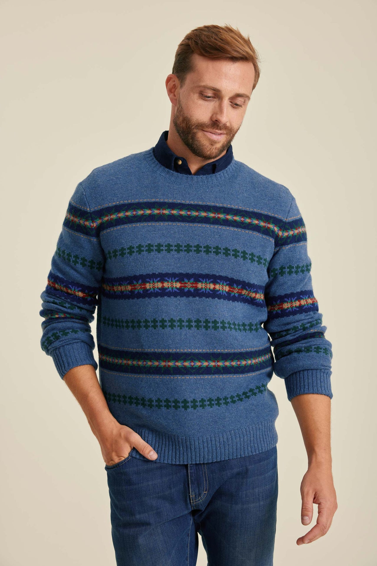 Man wearing a blue patterned sweater against a beige background