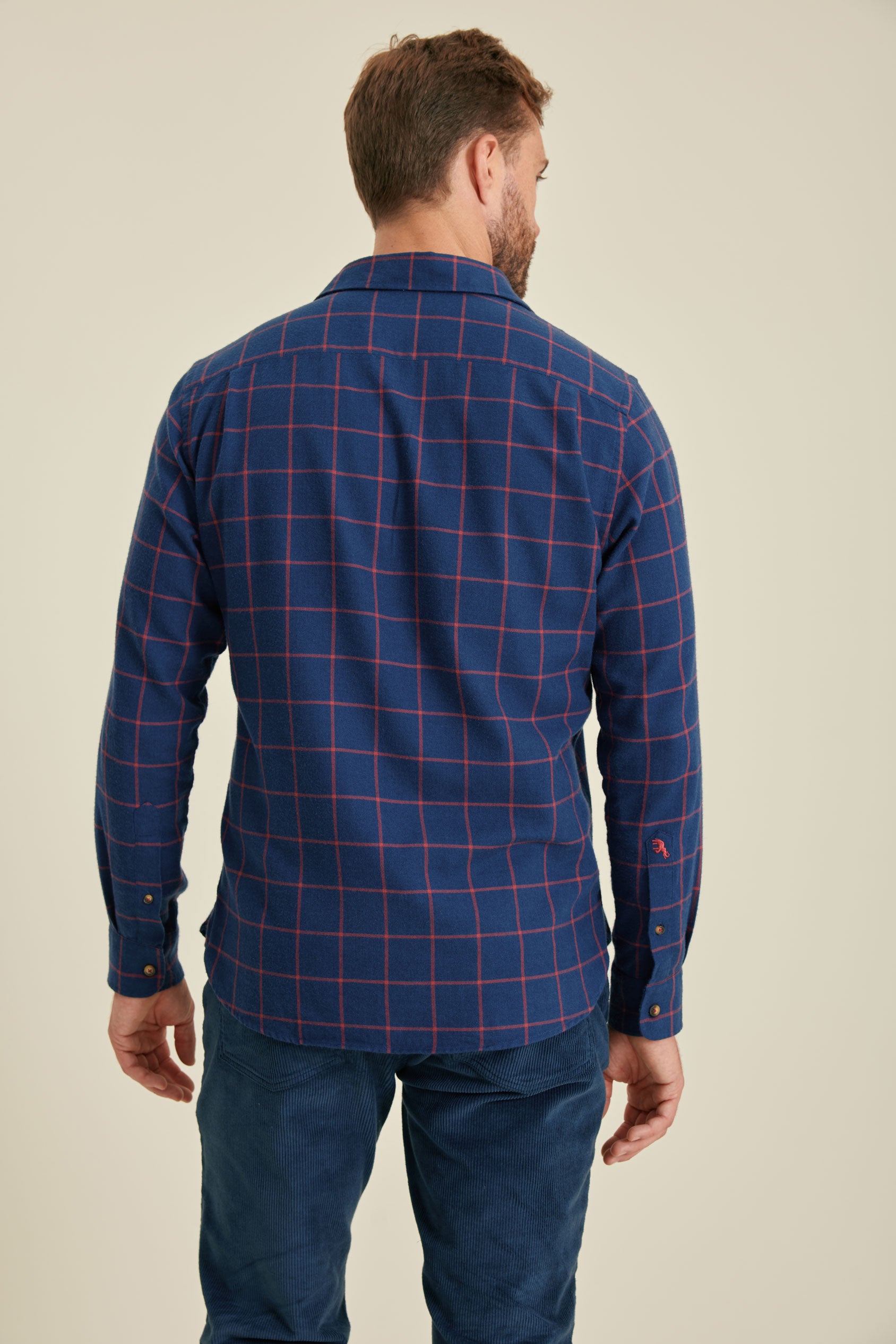 Man wearing a blue plaid shirt against a beige background