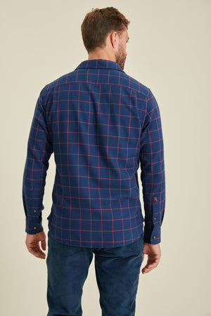 Man wearing a blue plaid shirt against a beige background