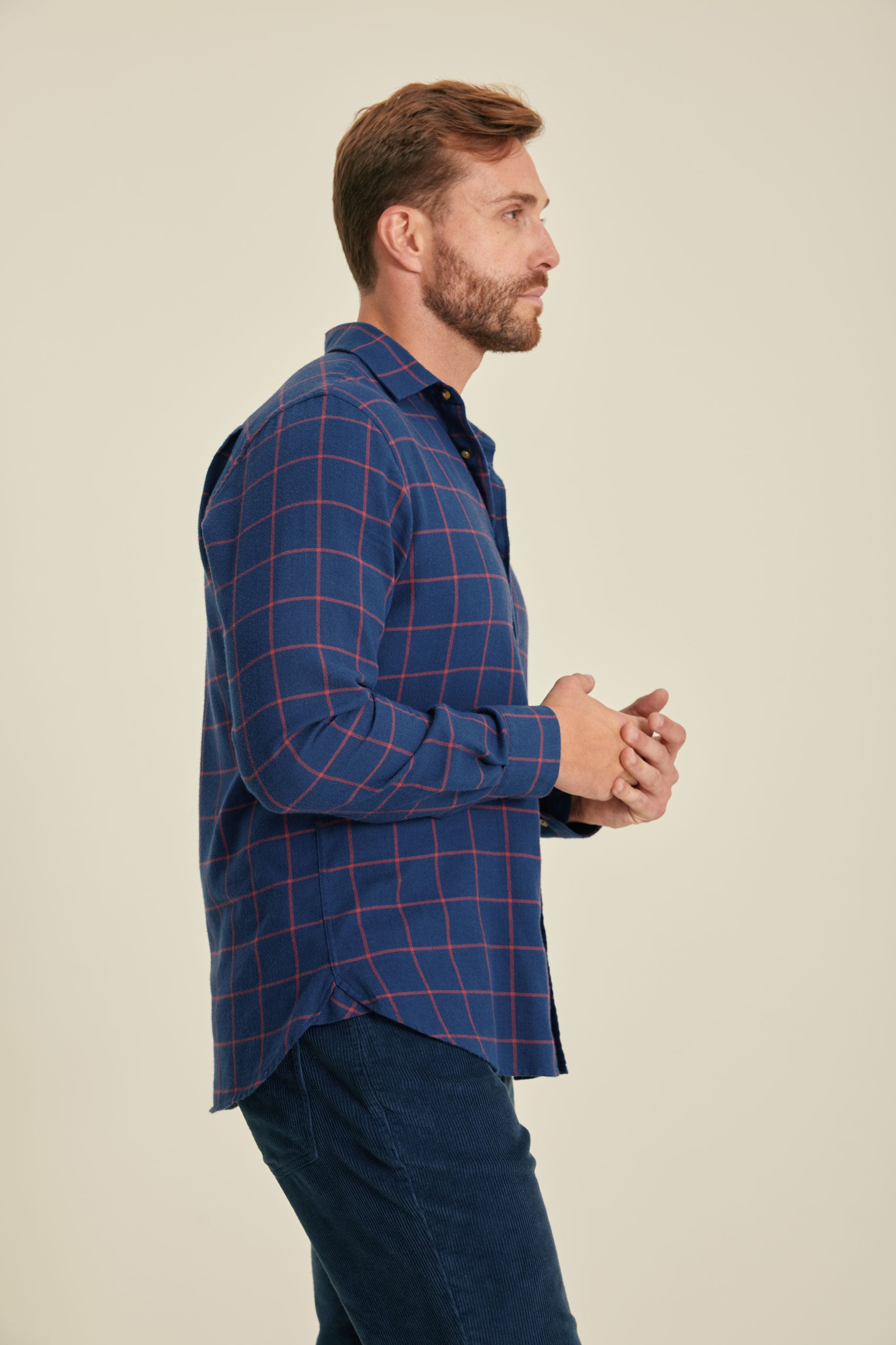 Man wearing a blue checkered shirt against a beige background
