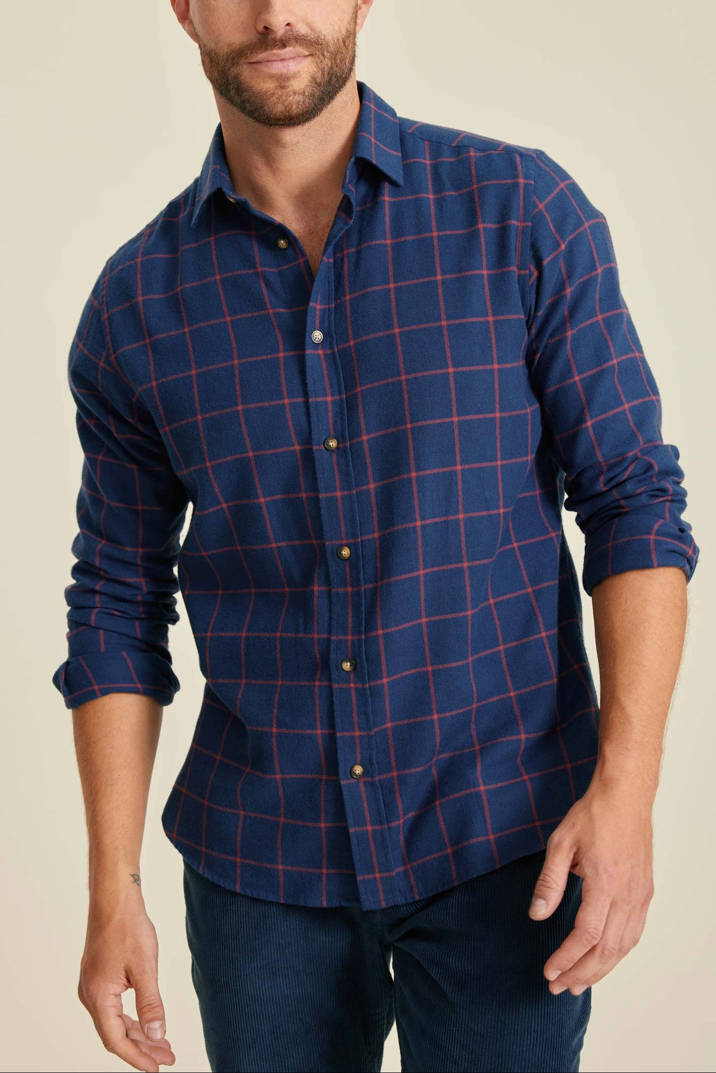 Man wearing a blue plaid shirt against a beige background