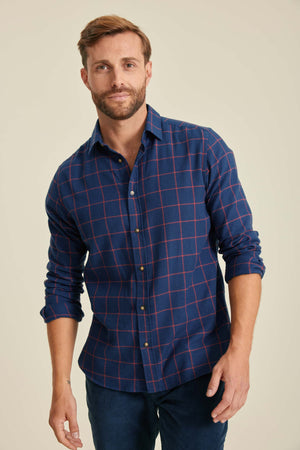 Man wearing a blue plaid shirt against a beige background