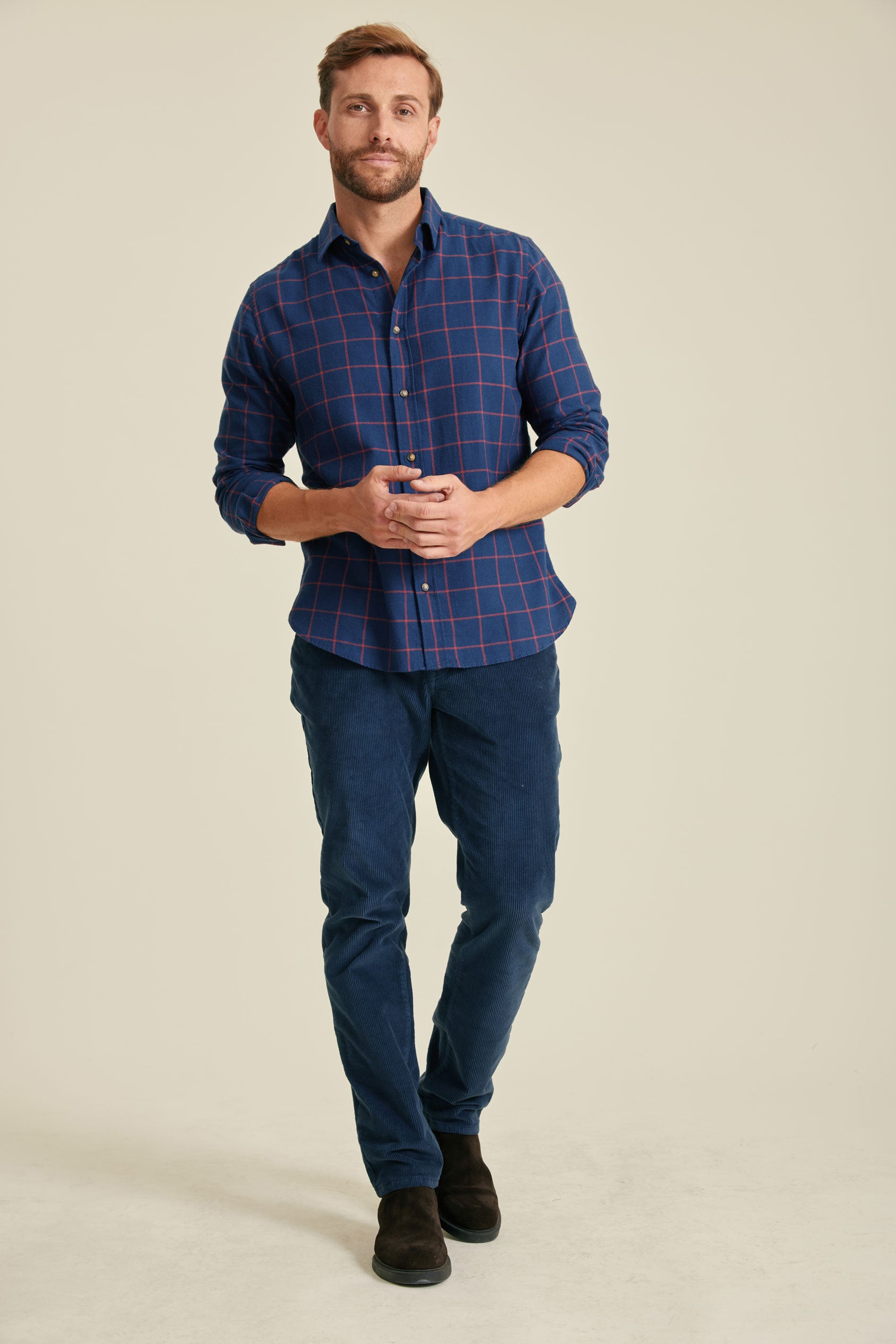 Man wearing a blue plaid shirt and jeans on a beige background