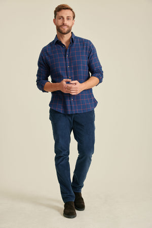 Man wearing a blue plaid shirt and jeans on a beige background