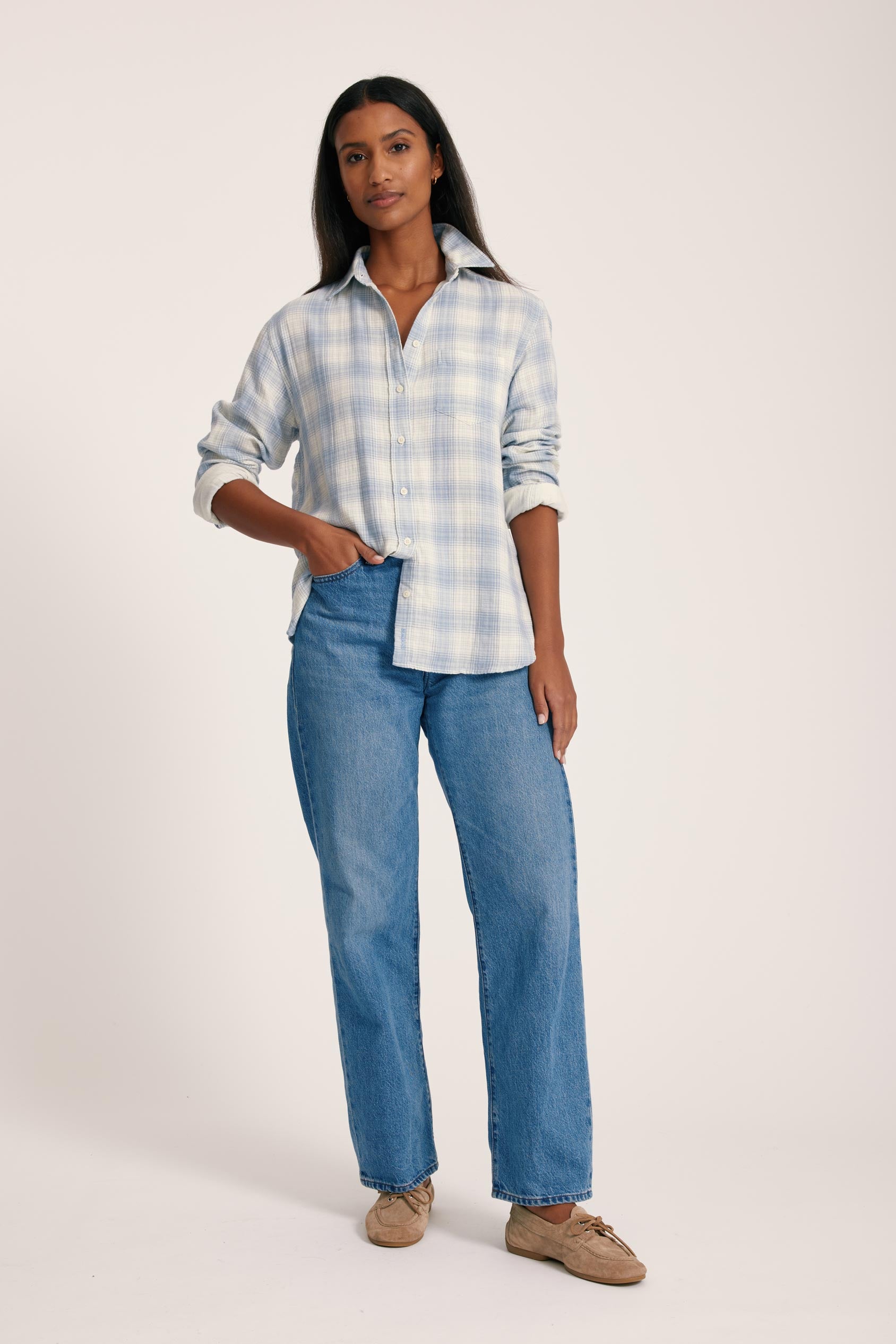 Woman wearing a blue plaid shirt and jeans on a white background