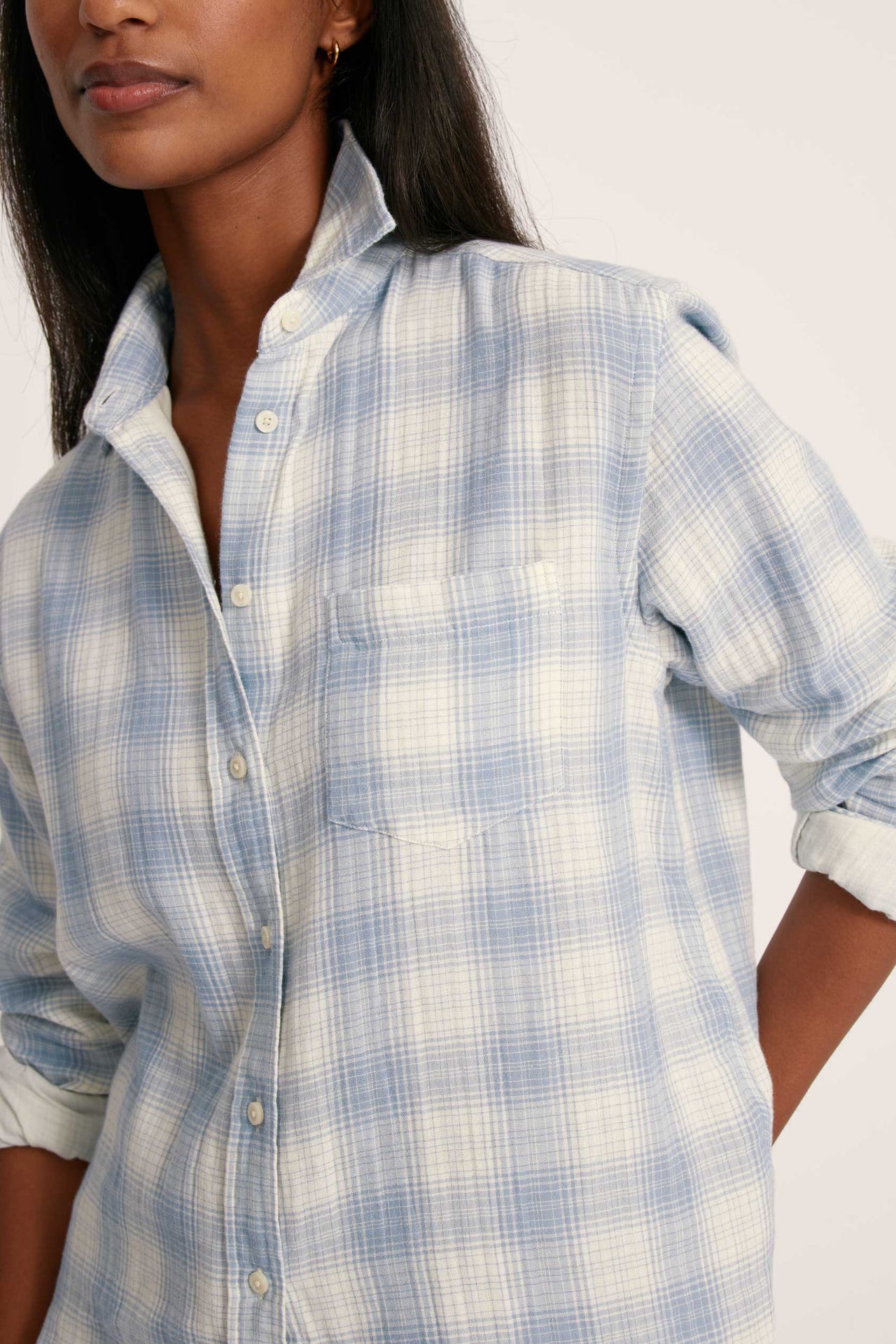 Woman wearing a blue and white checkered shirt against a plain background