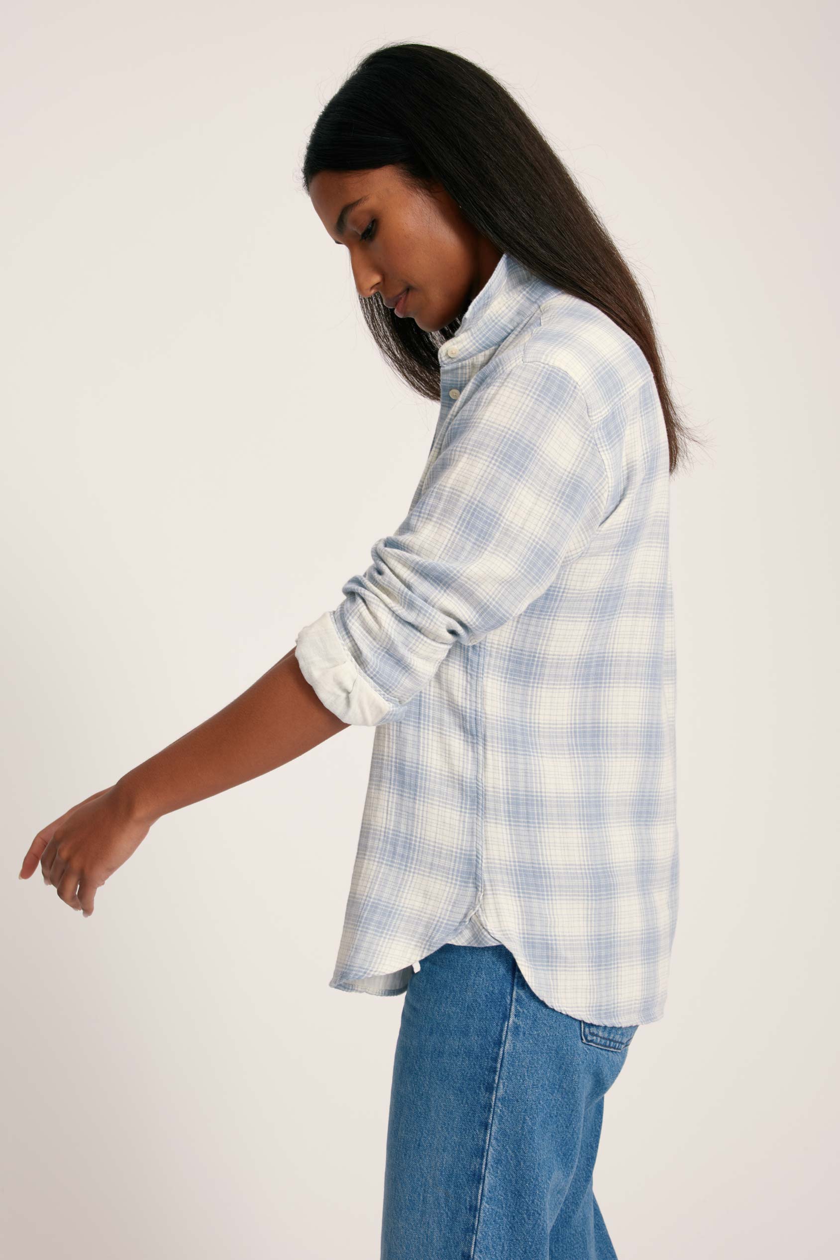 Woman wearing a light blue plaid shirt and jeans on a white background