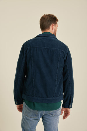 Man wearing a dark blue jacket and light blue jeans on a beige background