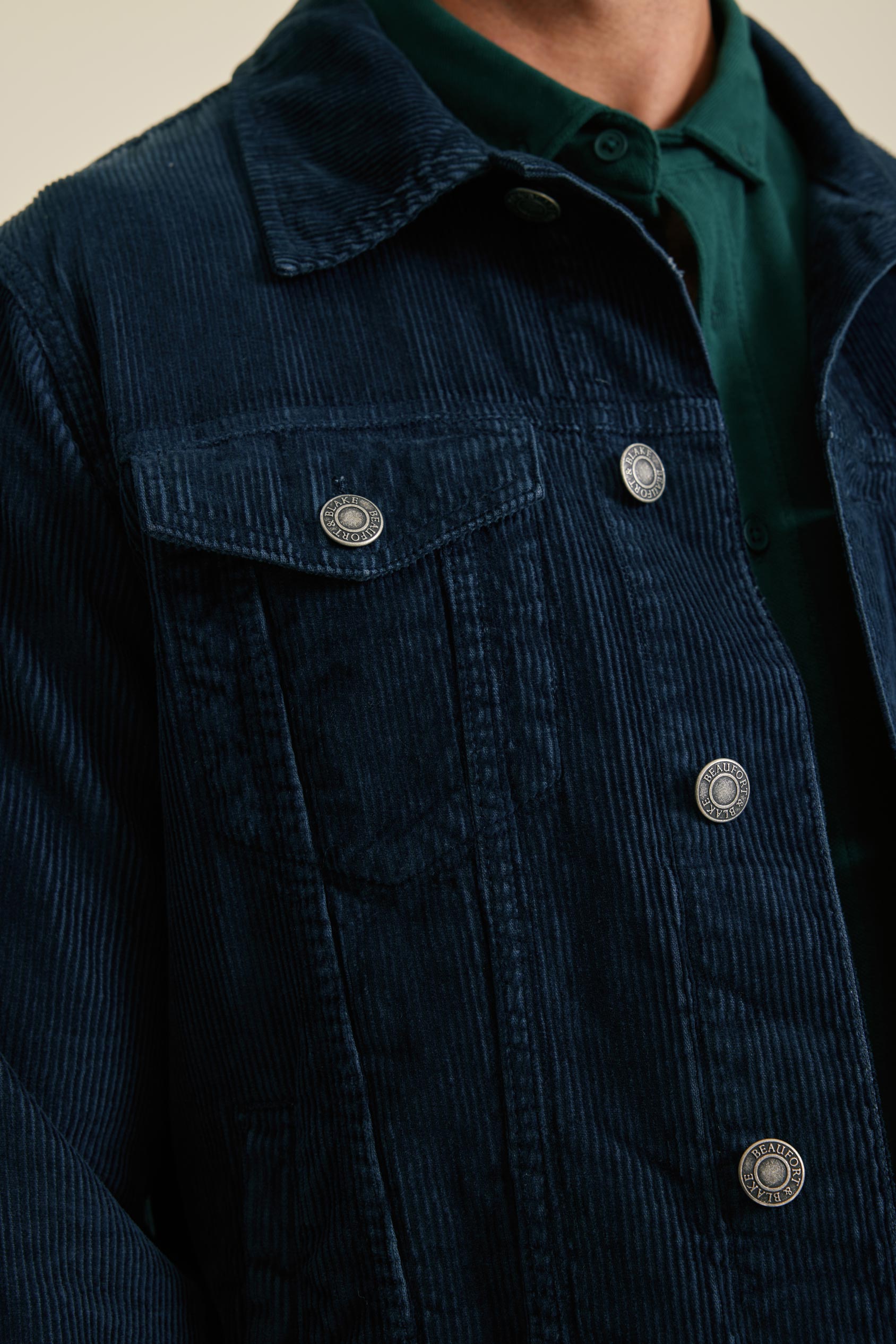 Navy blue corduroy jacket with silver buttons on a neutral background