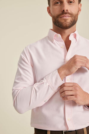 Man wearing a light pink dress shirt against a plain background
