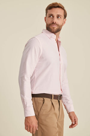 Man wearing a light pink dress shirt and beige pants on a beige background