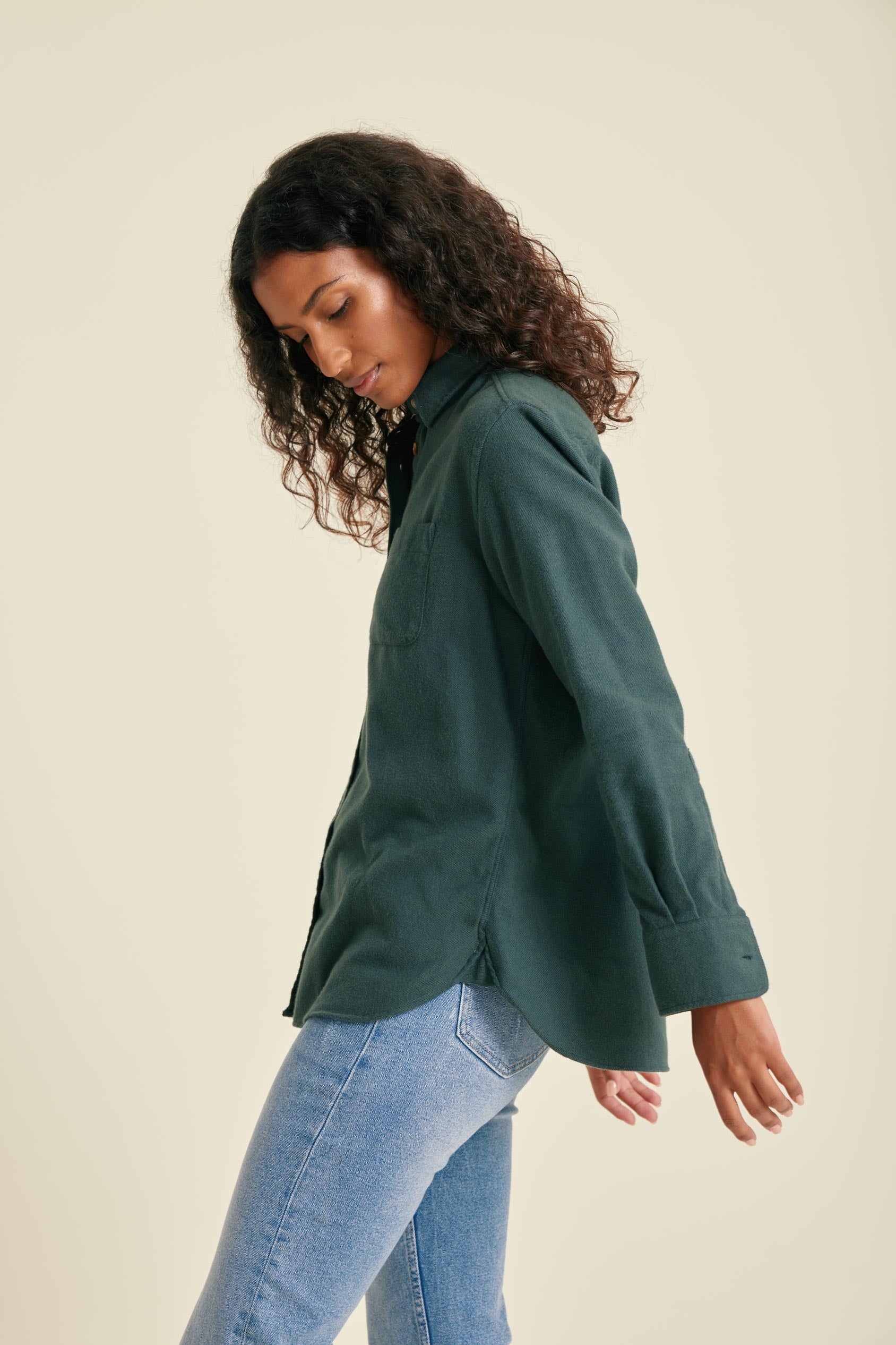 Woman wearing a green shirt and blue jeans on a beige background
