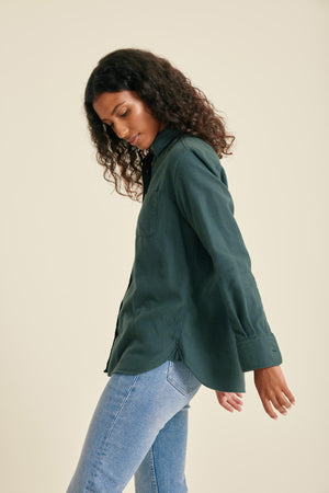 Woman wearing a green shirt and blue jeans on a beige background