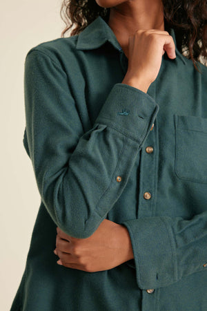 Teal shirt with buttons worn by a person on a beige background