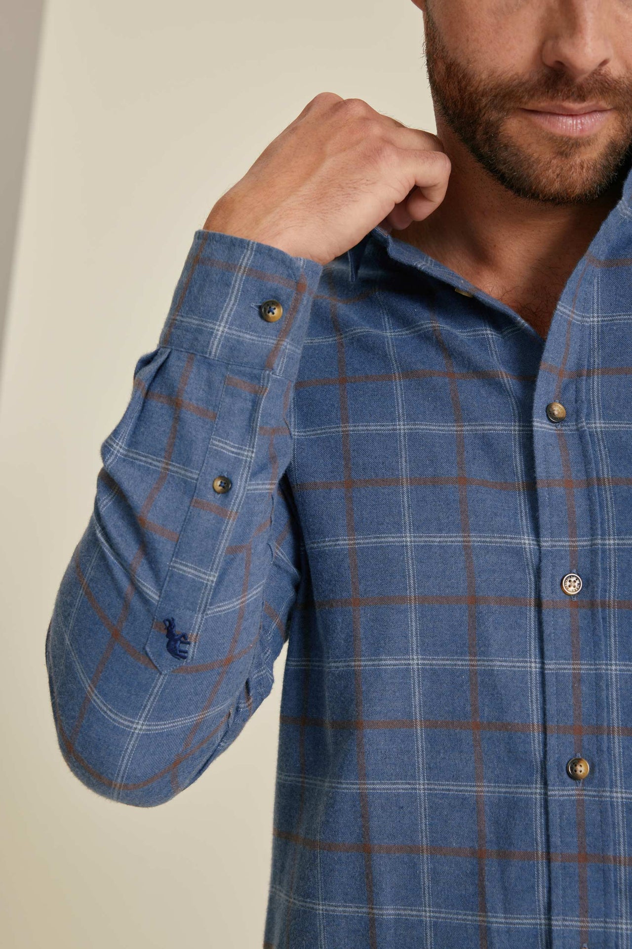 Man wearing a blue plaid shirt with a neutral background