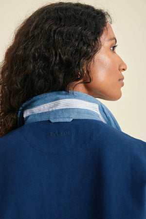 Person wearing a blue jacket with a visible brand logo on a plain background