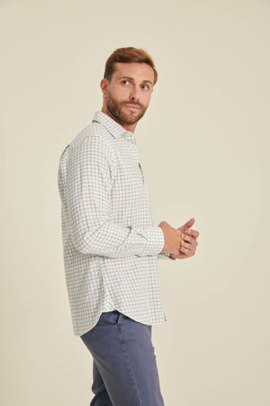 Man wearing a checkered shirt and blue pants against a beige background