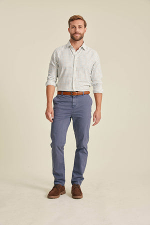 Man wearing a checkered shirt, blue pants, and brown shoes on a beige background
