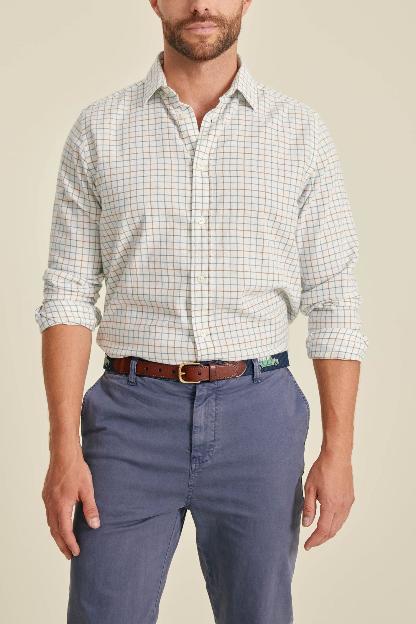Man wearing a checkered shirt and blue pants on a beige background