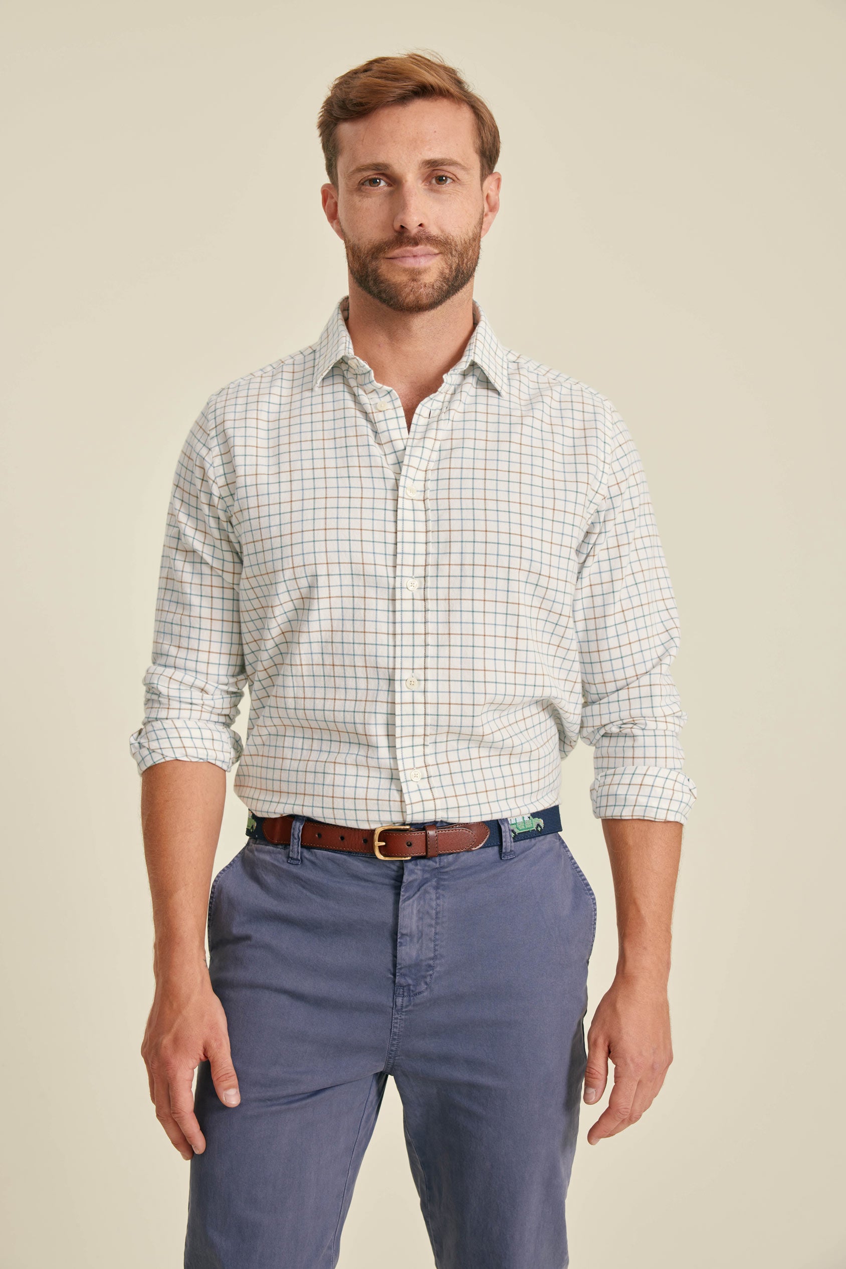 Man wearing a checkered shirt and blue pants on a beige background