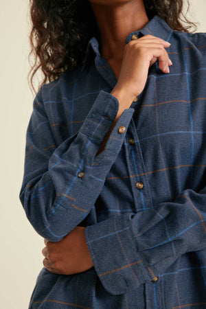 Person wearing a blue checkered shirt with a neutral background