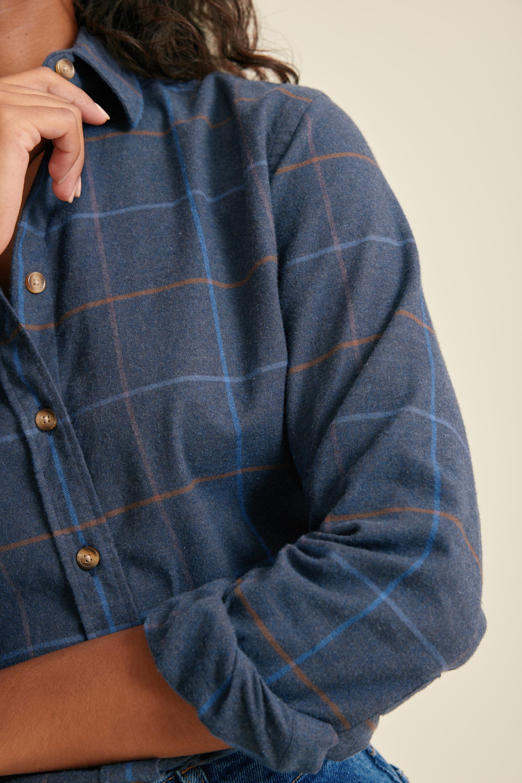 Blue plaid shirt with buttons on a neutral background