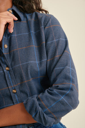Blue plaid shirt with buttons on a neutral background