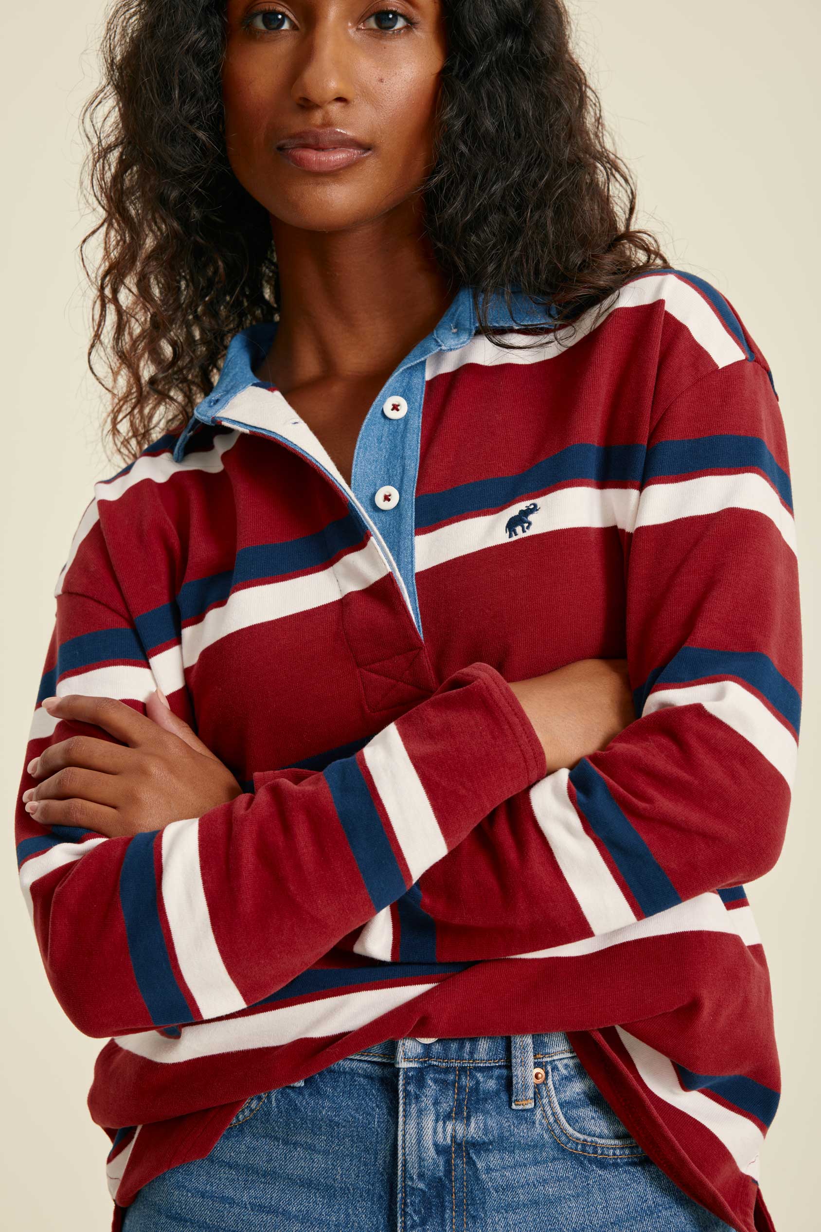 Woman wearing a red, white, and blue striped shirt with a brand logo on a beige background