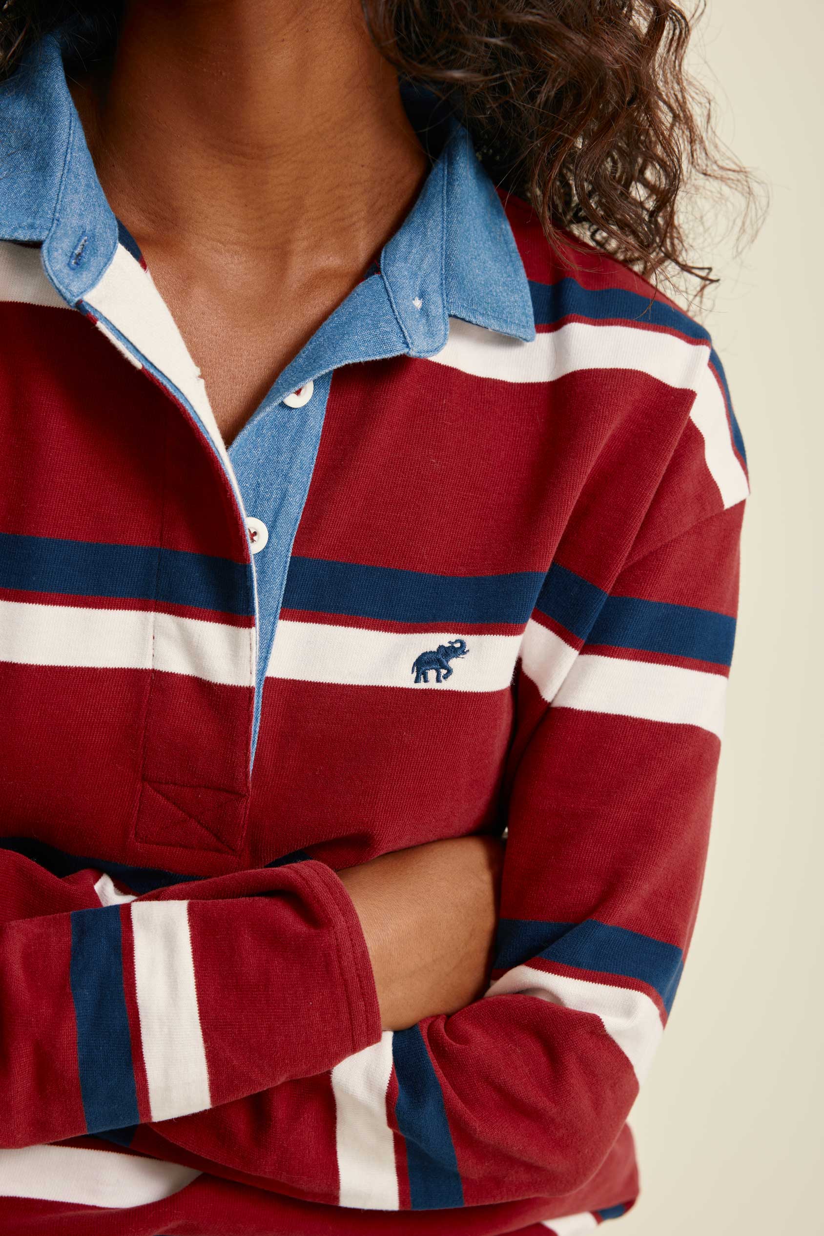 Red, white, and blue striped rugby shirt with a brand logo on a neutral background